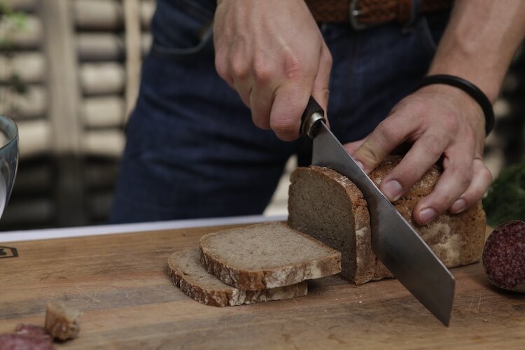 Mann schneidet mit Brotmesser ein Brot