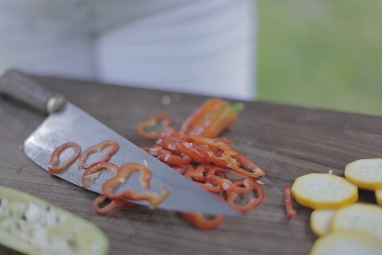 Messer mit dünn geschnittenem Gemüse auf einem Holzschniedebrett