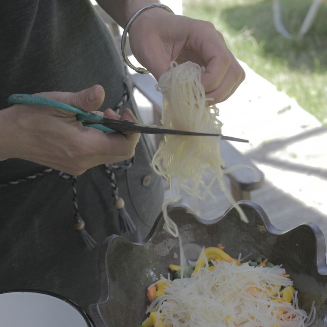 Frau schneidet Glasnudeln mit einer Kochschere