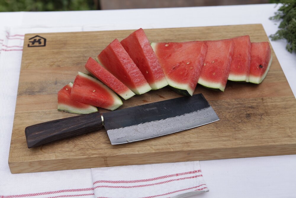 Holzbrett mit asiatischem Messer und geschnittenen Melonenscheiben darauf