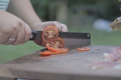 Tomate wird mit Tomatenmesser in dünne Scheiben geschnitten